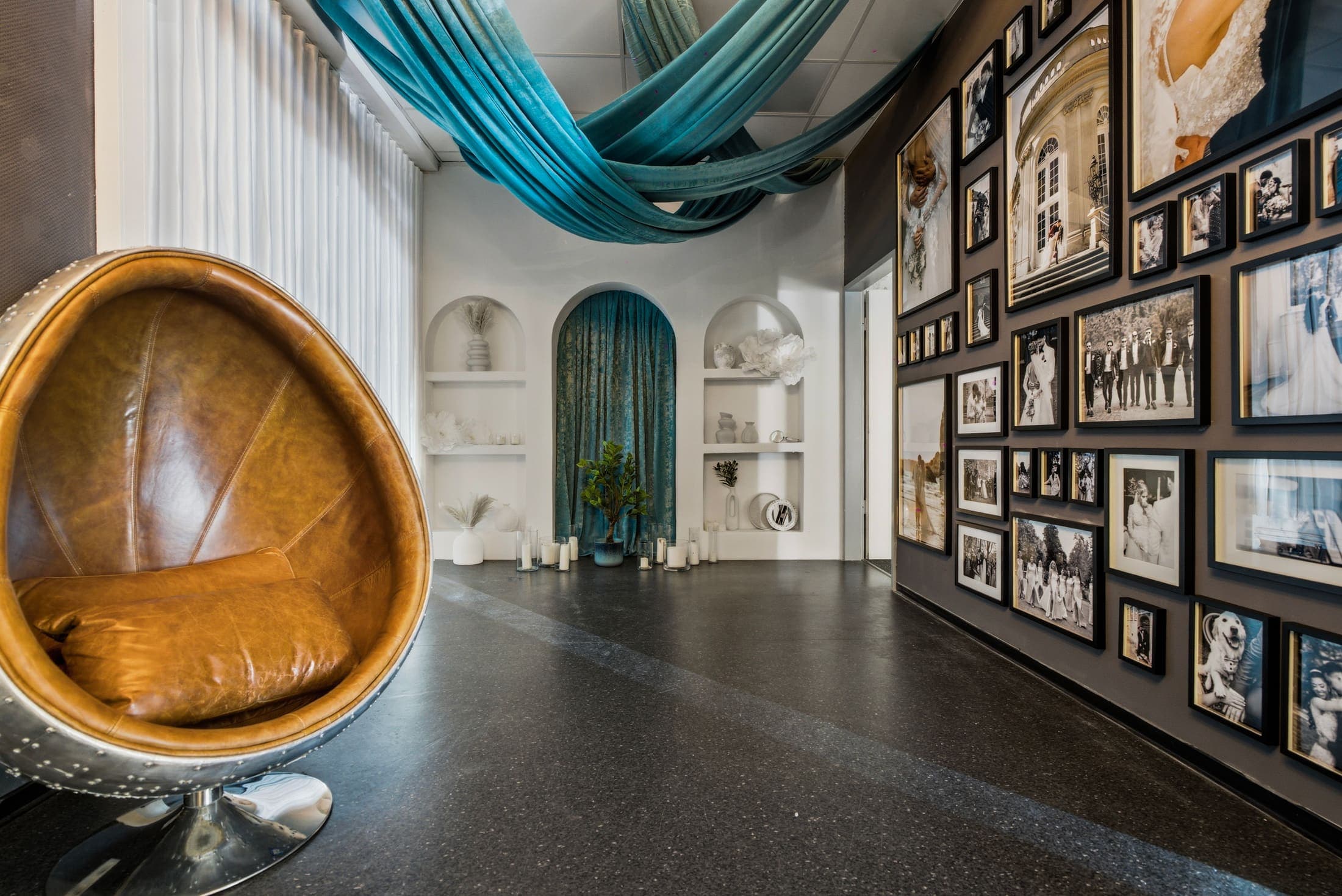 Bögen-Kulisse mit Egg-Chair, petrolfarbenen Stoffbahnen und Galerie-Bilderwand